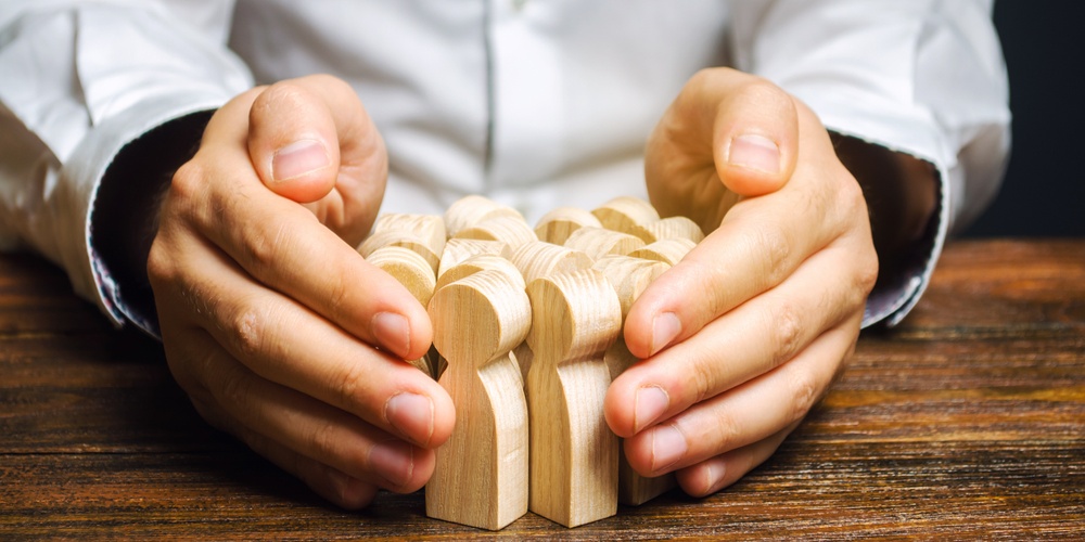 two hands holding wooden blocks of people together